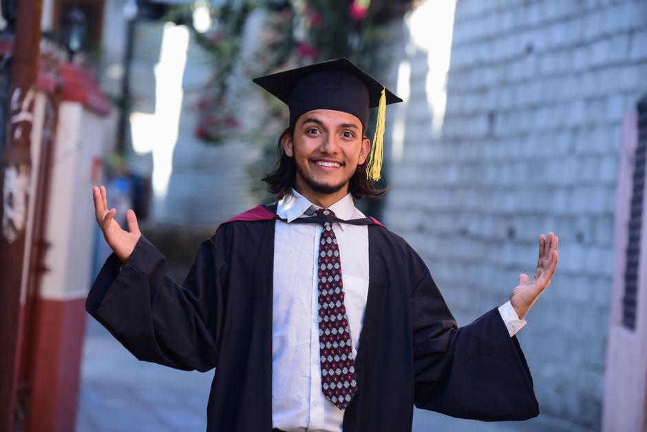 Smiling graduate celebrating success outdoors in academic regalia.